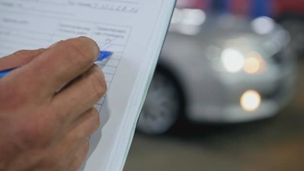 A close-up of a car's VIN number being checked by a buyer, highlighting the importance of verifying vehicle history.