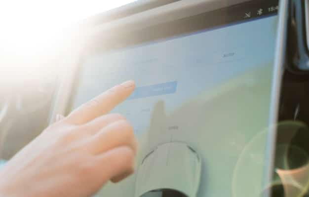 A close-up of a car's infotainment system displaying real-time interest rates and financing options, with a finger gently touching the screen.
