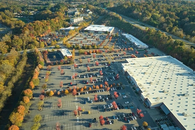 A high-angle shot of a Tesla Gigafactory in Nevada, showing rows of vehicles undergoing final inspection before export. Solar panels cover the roof of the factory.