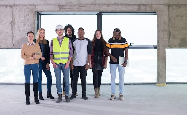 Group of diverse workers standing in front of an electric vehicle factory, wearing safety gear and smiling. The background shows the factory building and several electric vehicles parked nearby.