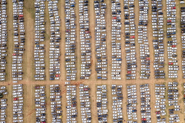 An aerial view of a large automotive factory with many unfinished electric vehicles parked around it. The image highlights the scale of the production slowdown and the impact on inventory.