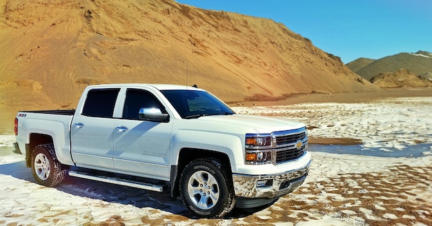 The 2025 Chevrolet Silverado 1500 is shown driving on a slightly uneven gravel road, highlighting its suspension system as it absorbs the bumps. The truck appears stable and composed in the image.