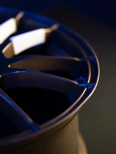 A close-up shot of the 2025 Volkswagen Golf GTI's wheel and suspension system, highlighting the adaptive dampers and performance tires. The focus is on the intricate details of the engineering.